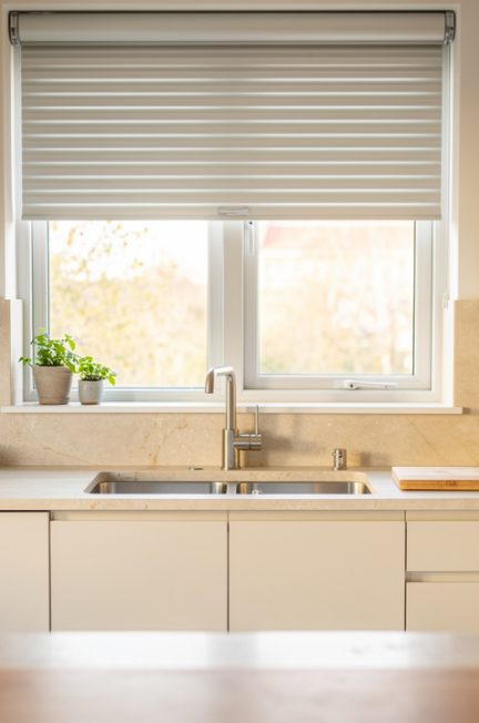 Cuisine rénovée lumineuse avec une fenêtre équipée d’un volet roulant discret en aluminium, éclairage naturel et finitions claires.