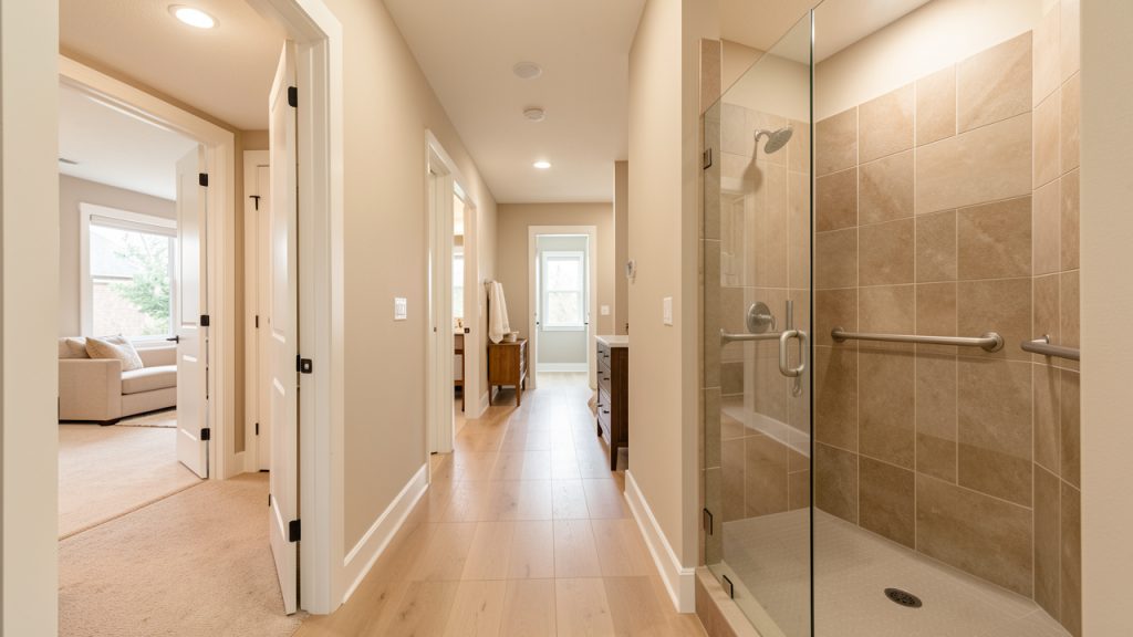 Intérieur lumineux d’une maison adaptée avec un couloir dégagé et une salle de bains sécurisée, dans une ambiance chaleureuse sans personnes.