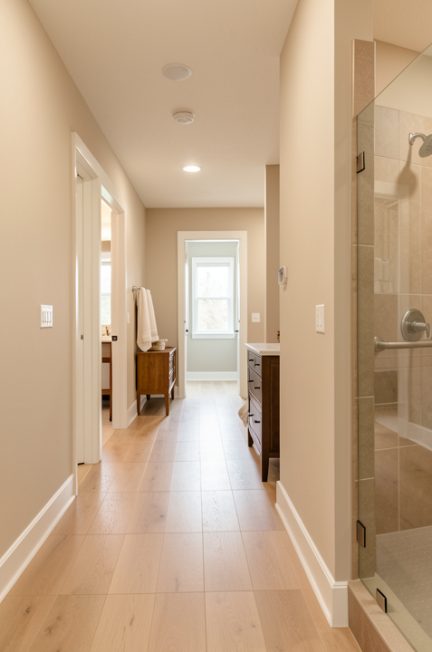 Intérieur lumineux d’une maison adaptée avec un couloir dégagé et une salle de bains sécurisée, dans une ambiance chaleureuse sans personnes.